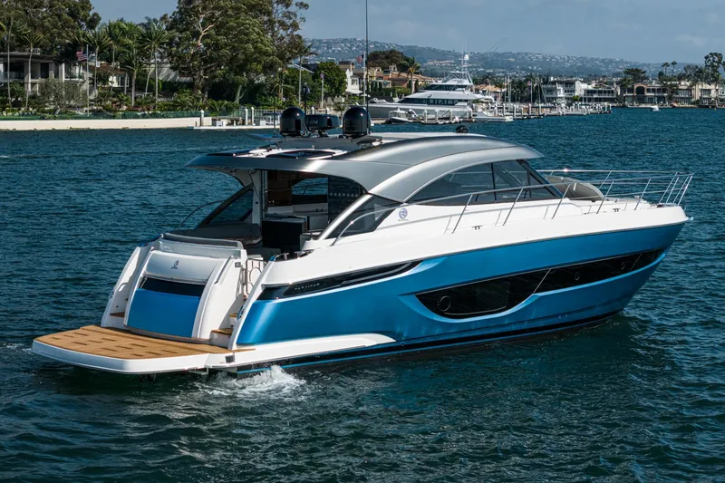 Slide: The Image of 2024 Riviera 4600 Sport Yacht cruising on a serene waterfront. - 11