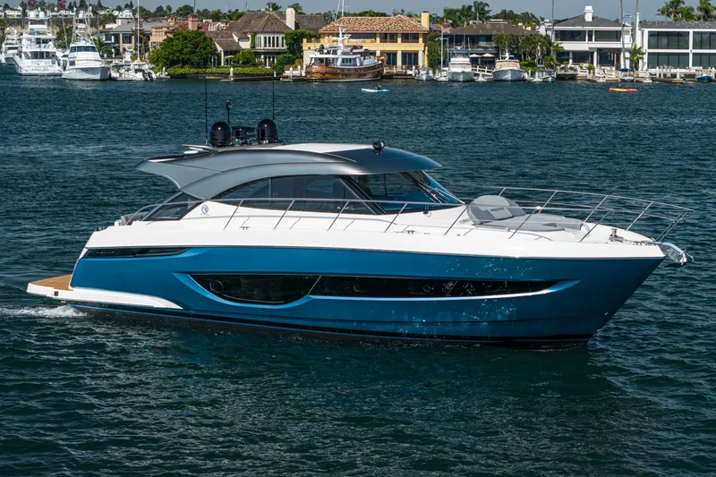 Slide: The Image of 2024 Riviera 4600 Sport Yacht cruising on a serene waterfront. - 14