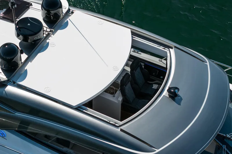 Slide: The Image of 2024 Riviera 4600 Sport Yacht with sleek design and open sunroof on the water. - 18