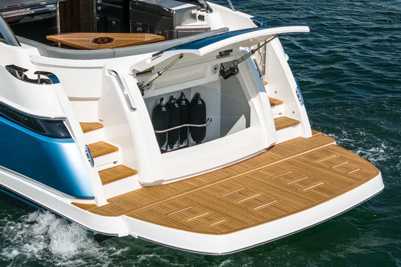 Slide: The Image of 2024 Riviera 4600 Sport Yacht with open swim platform and storage, docked on water. - 20