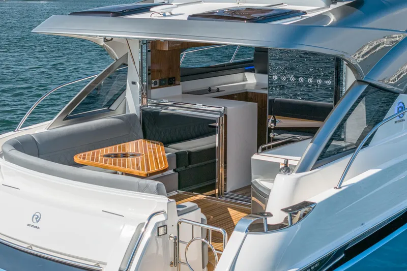 Slide: The Image of 2024 Riviera 4600 Sport Yacht with sleek design and luxurious outdoor seating area. - 24