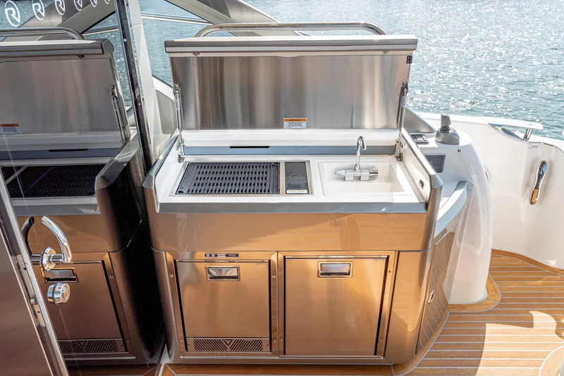Slide: The Image of Outdoor kitchen on 2024 Riviera 4600 Sport Yacht with grill and sink, overlooking water. - 29