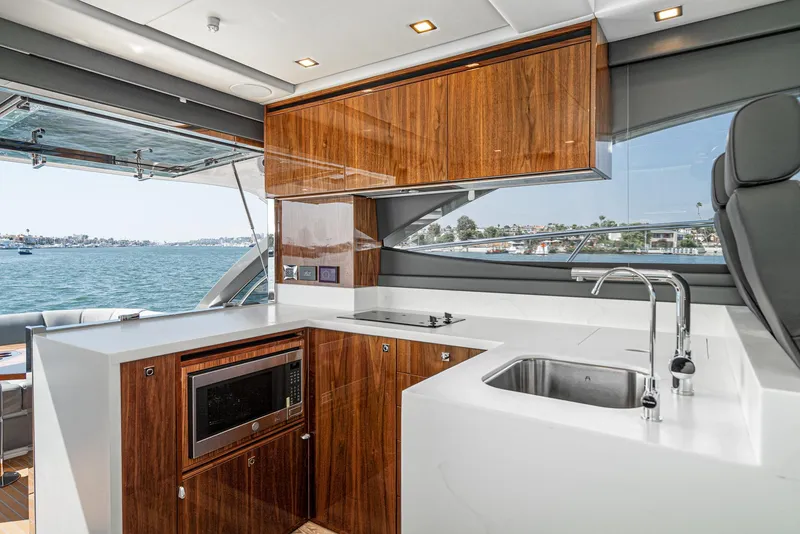 Slide: The Image of 2024 Riviera 4600 Sport Yacht kitchen with modern wood cabinetry and ocean view. - 34