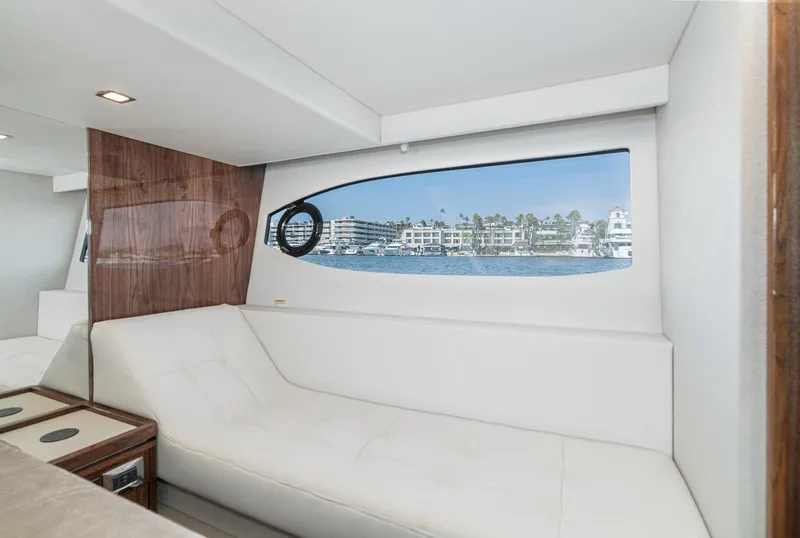 Slide: The Image of 2024 Riviera 4600 Sport Yacht interior with sleek white seating and scenic window view. - 46