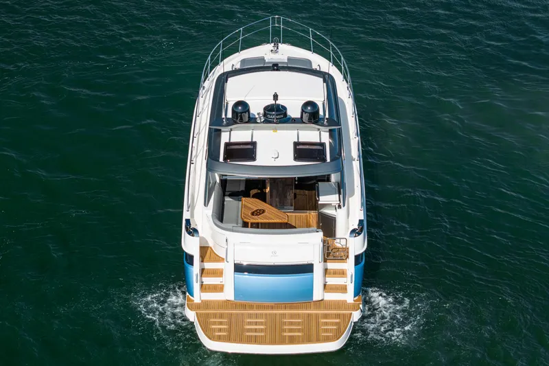 Slide: The Image of 2024 Riviera 4600 Sport Yacht cruising on open water, aerial rear view. - 9