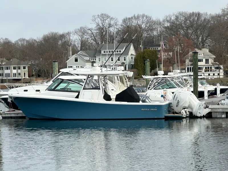 Slide: The Image of 2024 Regulator 31 boat docked in a marina with waterfront homes in the background. - 0
