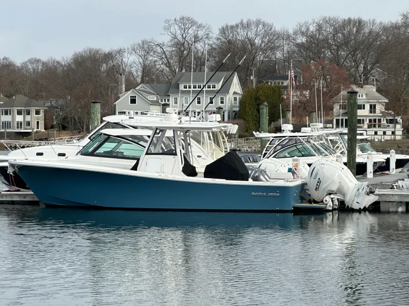Slide: The Image of 2024 Regulator 31 boat docked in a marina with waterfront homes in the background. - 1