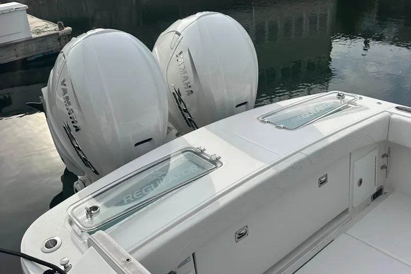 Slide: The Image of 2024 Regulator 31 boat with twin Yamaha outboard engines, docked on calm water. - 11