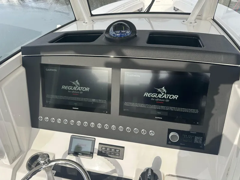 Slide: The Image of 2024 Regulator 31 boat dashboard with dual Garmin displays and compass. - 15