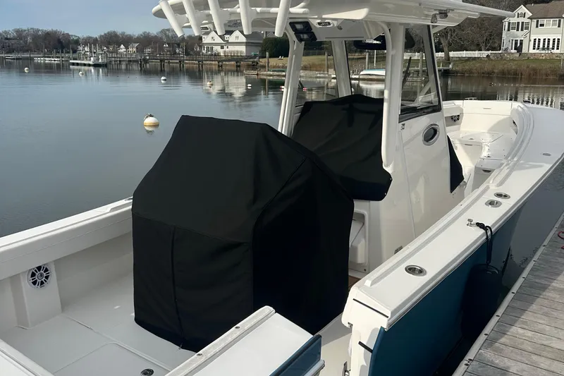 Slide: The Image of 2024 Regulator 31 boat docked, featuring covered seating and console, calm waterfront setting. - 5