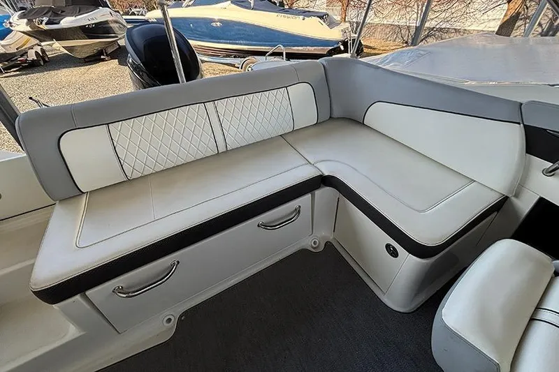 Slide: The Image of 2016 Sea Ray 220 Sundeck Outboard interior seating with white and gray upholstery. - 15
