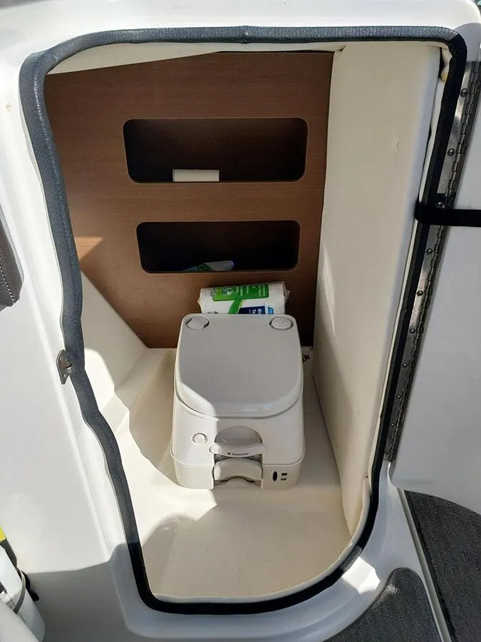 Slide: The Image of 2016 Sea Ray 220 Sundeck Outboard boat toilet compartment with storage shelves. - 4