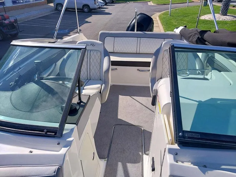 Slide: The Image of 2016 Sea Ray 220 Sundeck Outboard interior with seating and windshield, parked outdoors. - 6