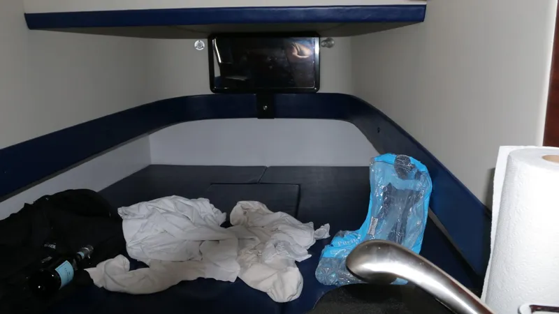 Slide: The Image of 2017 Mystic Powerboats M4200 cabin interior with bed, clothes, and a bottle. - 24