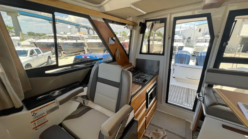 Slide: The Image of 2023 Cutwater C-288 interior with seating, kitchenette, and view of docked boats. - 17