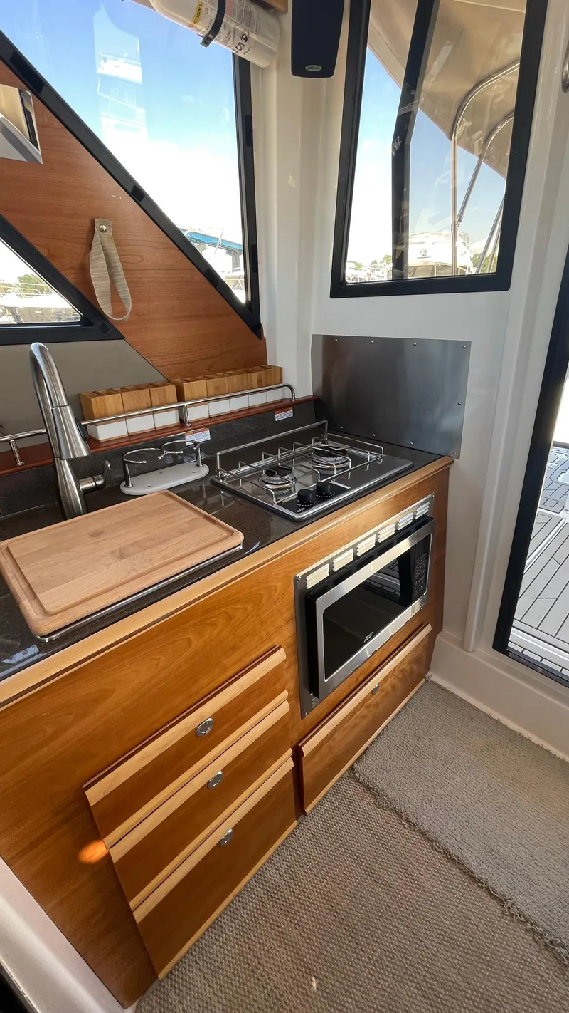 Slide: The Image of 2023 Cutwater C-288 boat kitchen with stove, oven, and wooden cabinetry. - 19