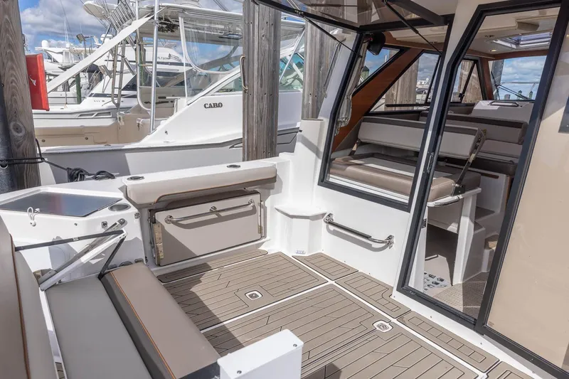 Slide: The Image of 2023 Cutwater C-288 boat interior with seating, wood flooring, and open cabin door. - 26