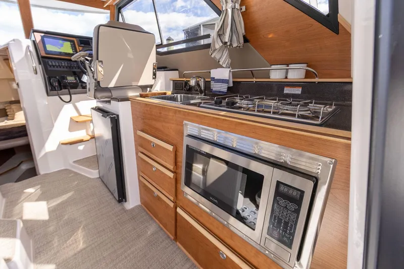 Slide: The Image of 2023 Cutwater C-288 boat interior with kitchen, featuring stove, microwave, and navigation area. - 29