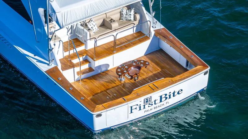Slide: The Image of Luxury Viking 2005 yacht with wooden deck, named "First Bite," cruising in clear waters. - 37