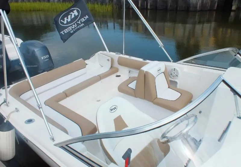 Slide: The Image of 2025 Key West 203 DFS boat interior with tan and white seating, docked by calm water. - 3