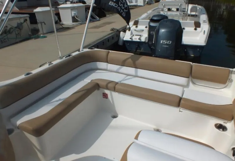 Slide: The Image of 2025 Key West 203 DFS boat interior with beige seating, docked near other boats. - 7