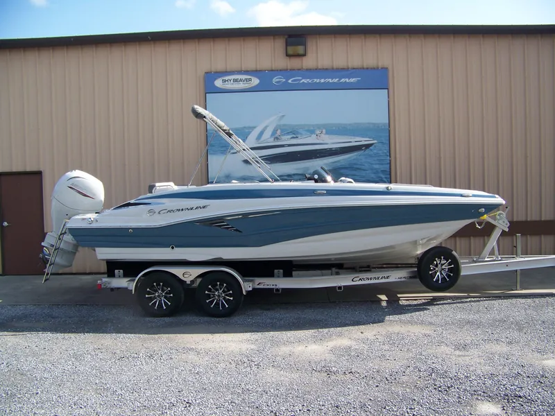 The Image of 2026 Crownline Eclipse E230 XS boat on trailer, parked outside a building. - 1