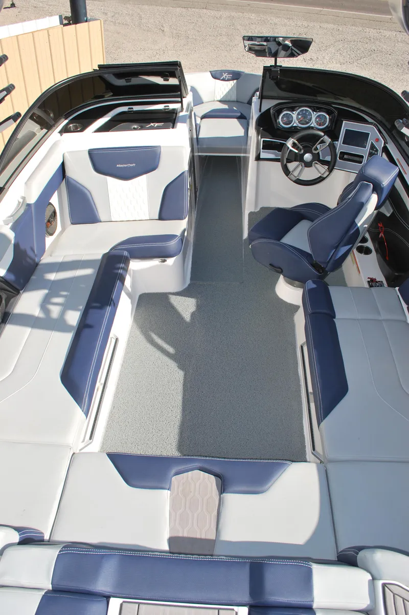 Slide: The Image of 2023 MasterCraft XT22 T boat interior with blue and white seating and modern dashboard. - 17