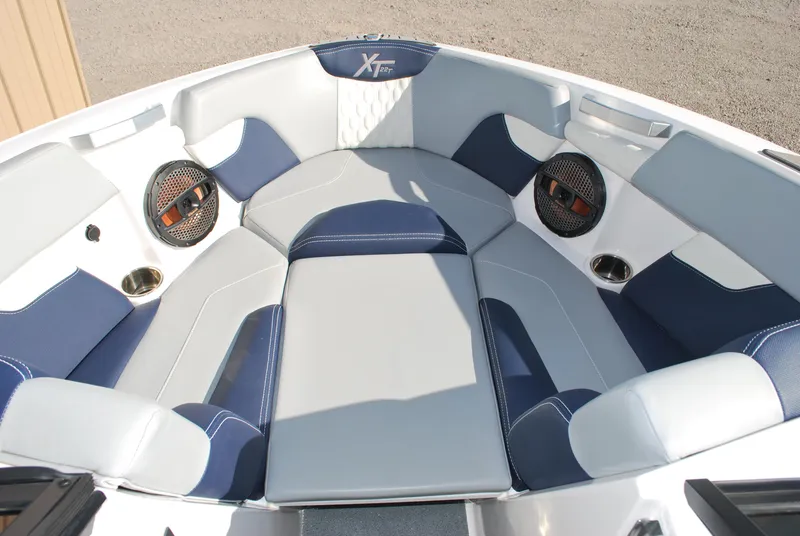 Slide: The Image of 2023 MasterCraft XT22 T boat interior with blue and white seating and built-in speakers. - 7