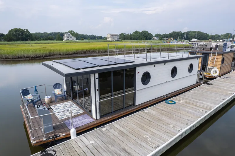 Slide: The Image of Modern 2025 Waterlodge Apart EL houseboat docked, featuring solar panels and spacious deck. - 0