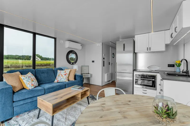 Slide: The Image of Modern Waterlodge Apart EL 2025 interior with cozy living area, kitchen, and scenic window view. - 14