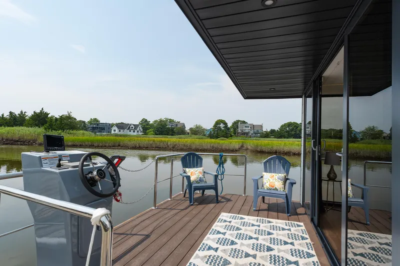 Slide: The Image of Houseboat deck with chairs, steering console, and scenic river view; Waterlodge Apart EL 2025 model. - 2