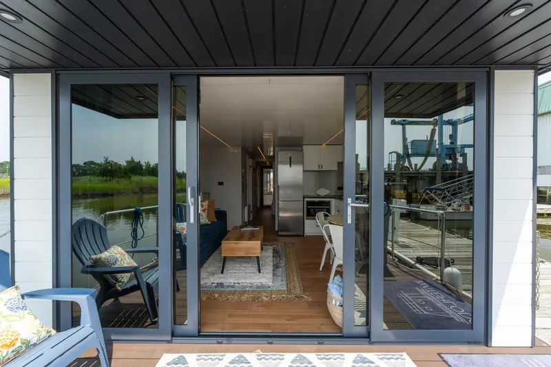 Slide: The Image of Modern Waterlodge Apart EL 2025 houseboat interior with glass doors, cozy seating, and scenic views. - 28