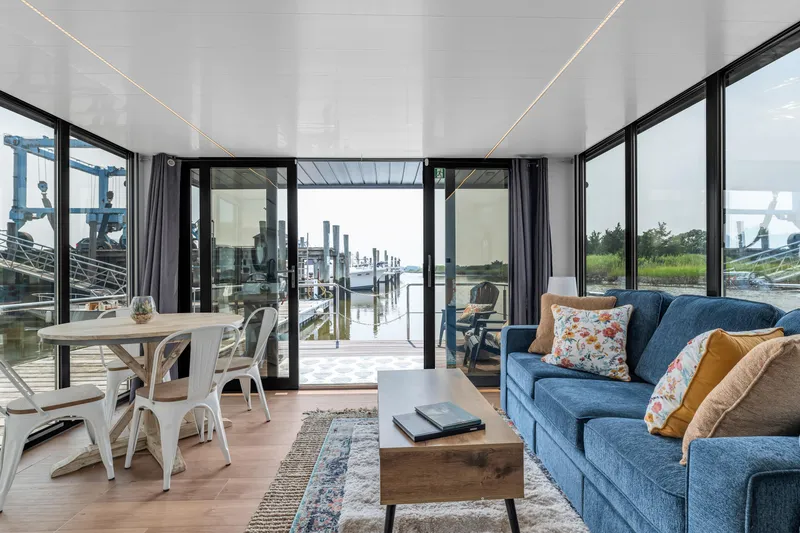 Slide: The Image of Modern Waterlodge Apart EL 2025 interior with cozy seating, dining area, and marina view. - 29
