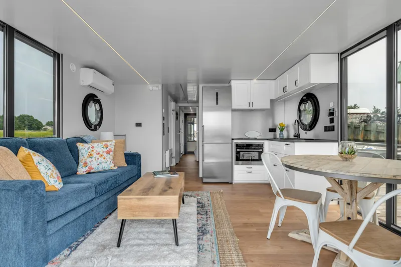 Slide: The Image of Modern Waterlodge Apart EL 2025 interior with blue sofa, kitchen, and dining area. - 3