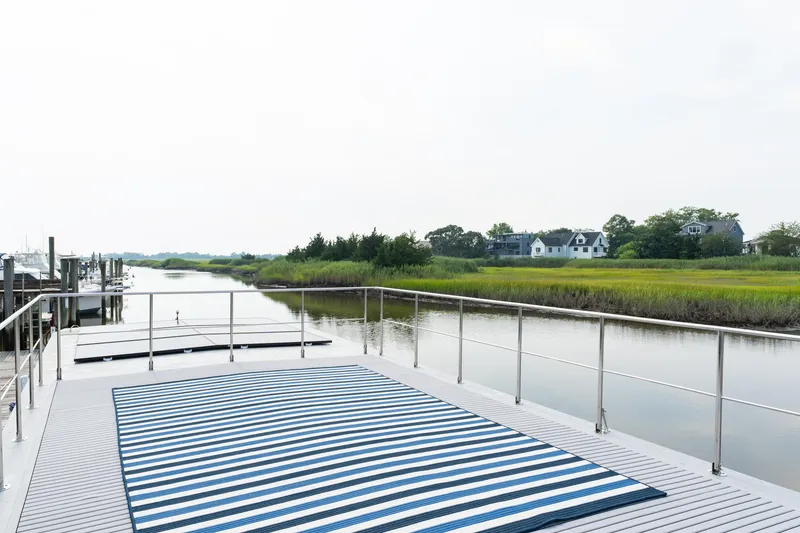 Slide: The Image of Houseboat deck with striped rug, overlooking serene river and lush greenery. Waterlodge Apart EL 2025. - 30
