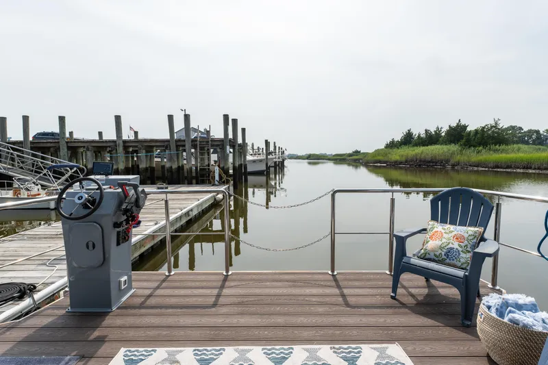 Slide: The Image of Waterlodge Apart EL 2025 houseboat docked by serene waters, featuring cozy outdoor seating. - 34