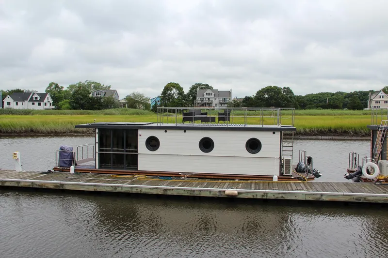 Slide: The Image of Houseboat on a river, Waterlodge Apart EL 2025 model, docked near grassy shoreline. - 39