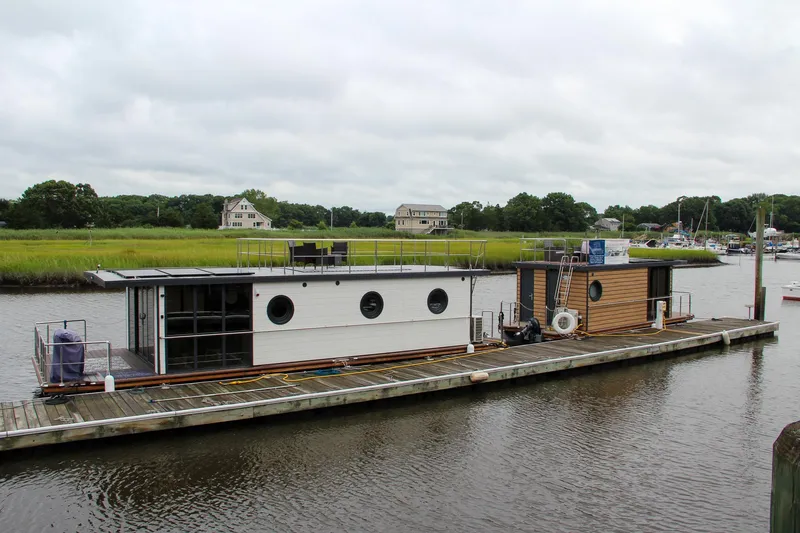 Slide: The Image of Modern Waterlodge Apart EL 2025 houseboat docked on a serene river with lush greenery. - 40
