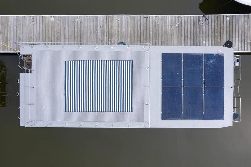 Slide: The Image of Aerial view of 2025 Waterlodge Apart EL houseboat with solar panels and striped deck canopy. - 5