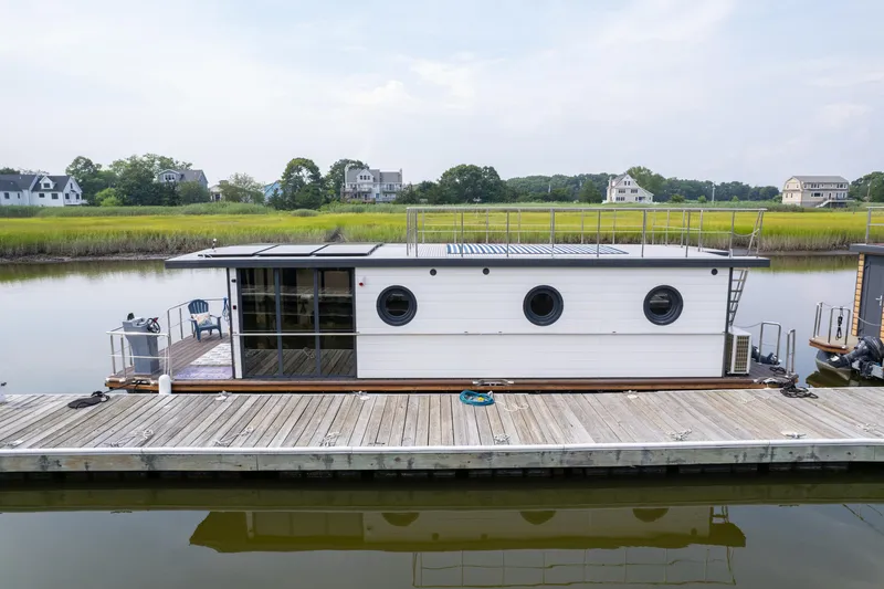 Slide: The Image of Modern 2025 Waterlodge Apart EL houseboat docked on serene waterway with scenic background. - 6