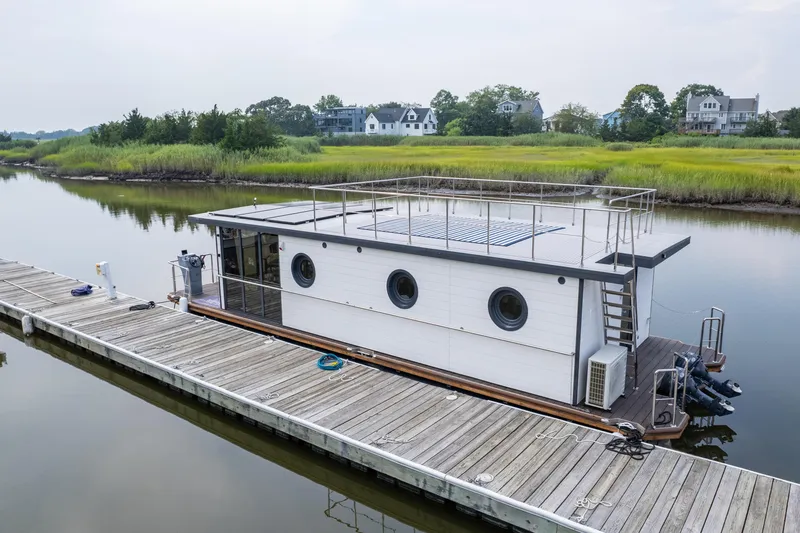 Slide: The Image of Modern 2025 Waterlodge Apart EL houseboat docked on a serene river with lush greenery. - 7