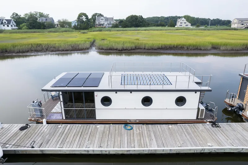 Slide: The Image of Modern Waterlodge Apart EL 2025 houseboat docked on serene waterway with lush greenery. - 8