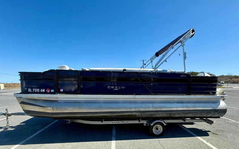 Slide: The Image of 2020 Crest Classic LX Fish 220 SF pontoon boat on trailer under clear blue sky. - 3
