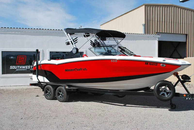 Slide: The Image of 2022 MasterCraft NXT24 boat in red and white, parked on a trailer outside a building. - 1