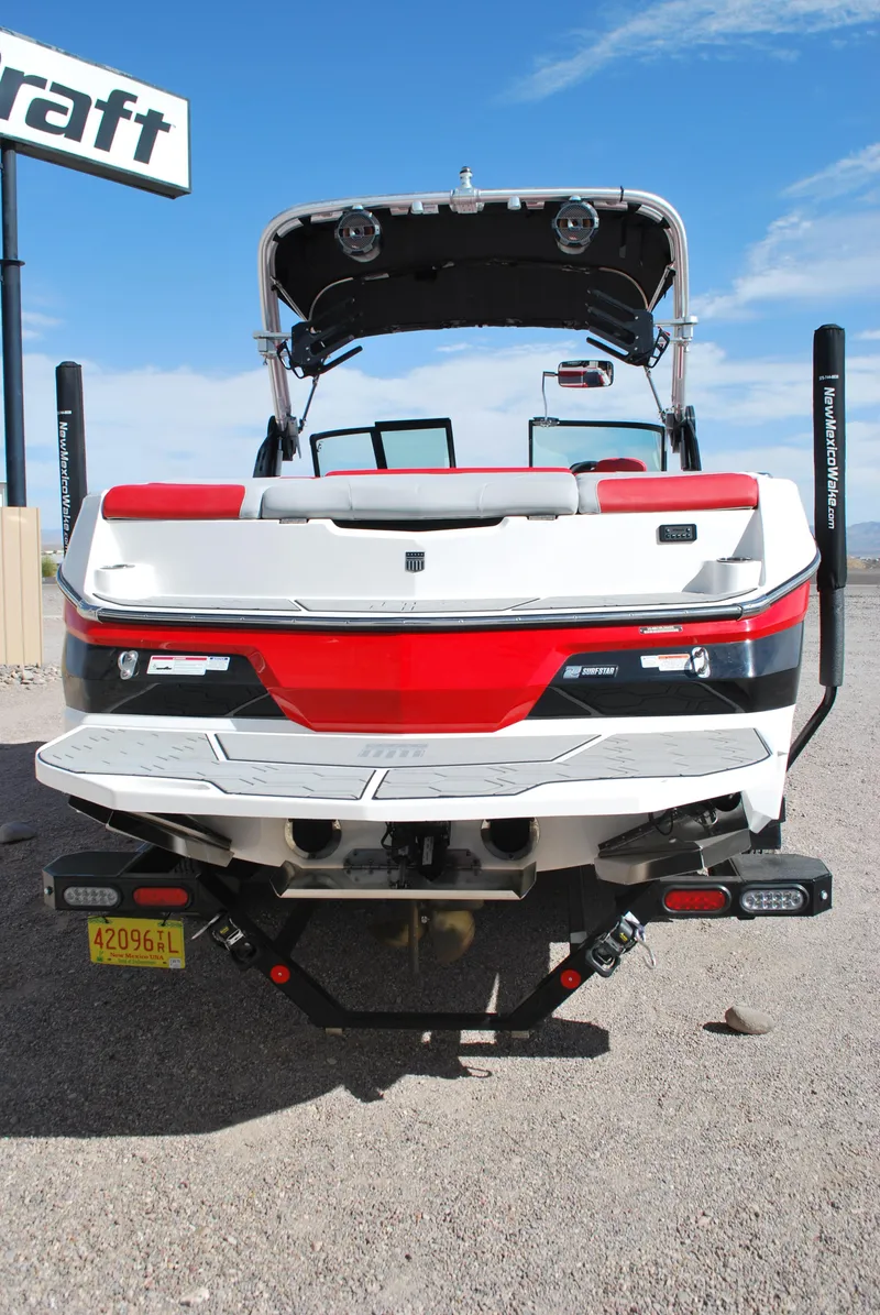 Slide: The Image of 2022 MasterCraft NXT24 boat, rear view, red and white design, parked outdoors. - 17