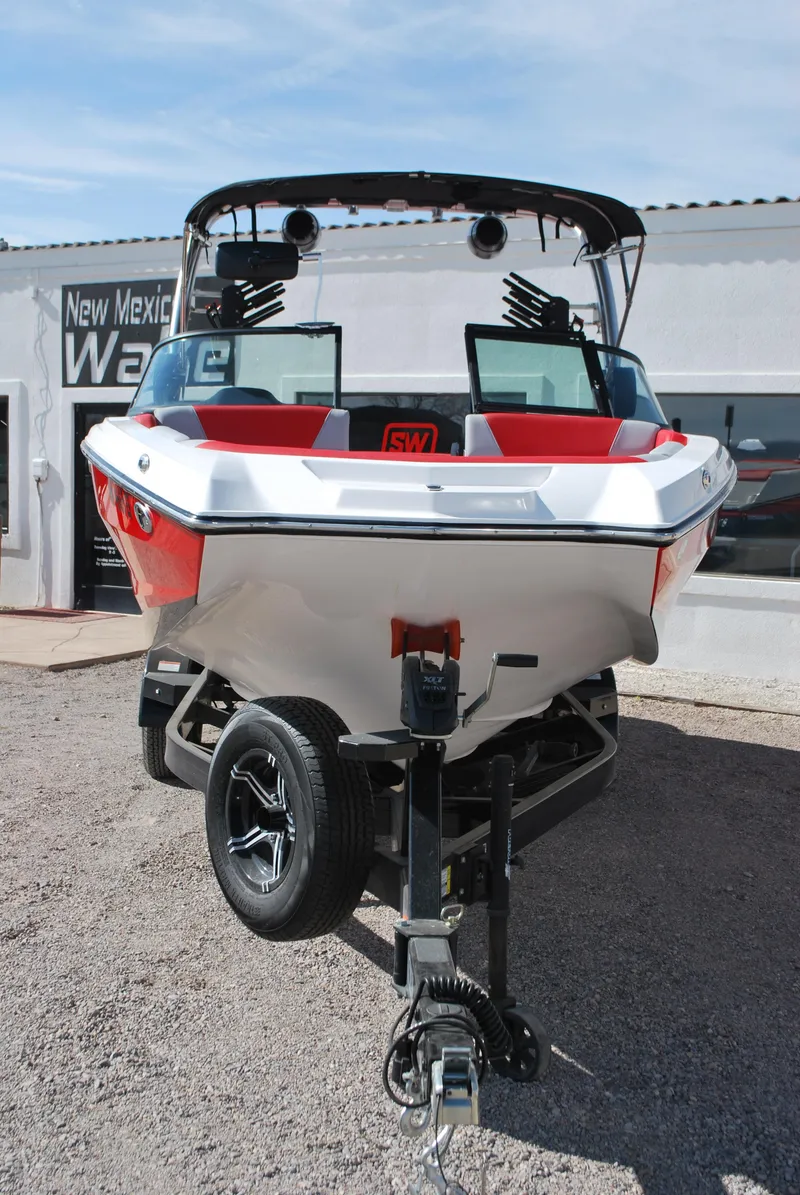 Slide: The Image of 2022 MasterCraft NXT24 boat on trailer, displayed outdoors with red and white design. - 2