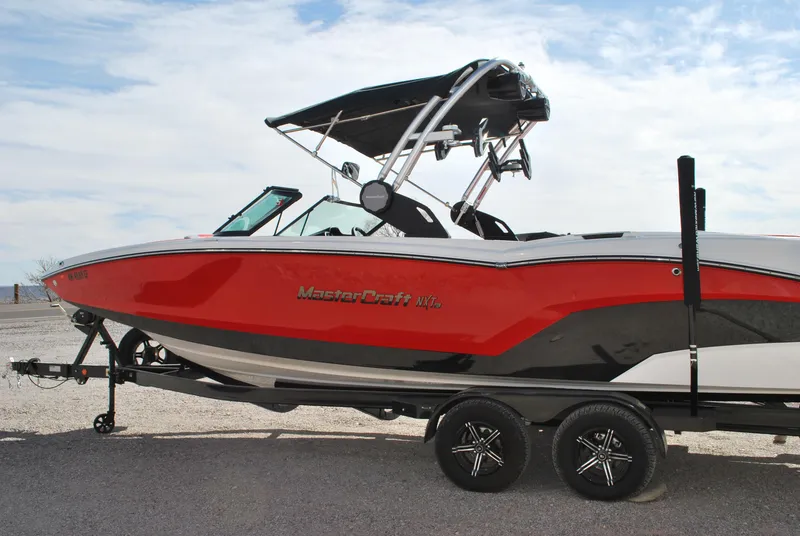 Slide: The Image of 2022 MasterCraft NXT24 boat in red and black on a trailer, side view. - 3