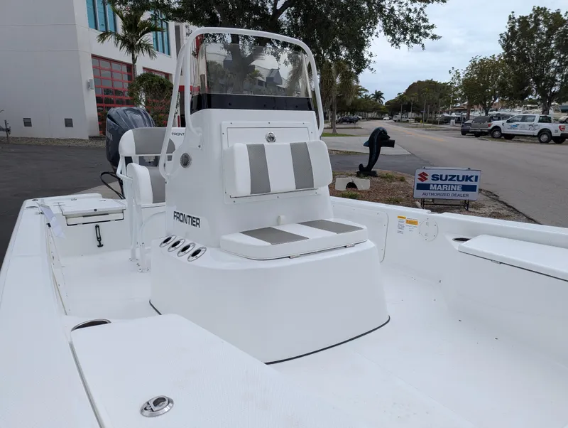 Slide: The Image of 2025 Frontier 2104 boat with white seating, parked near Suzuki Marine sign. - 6