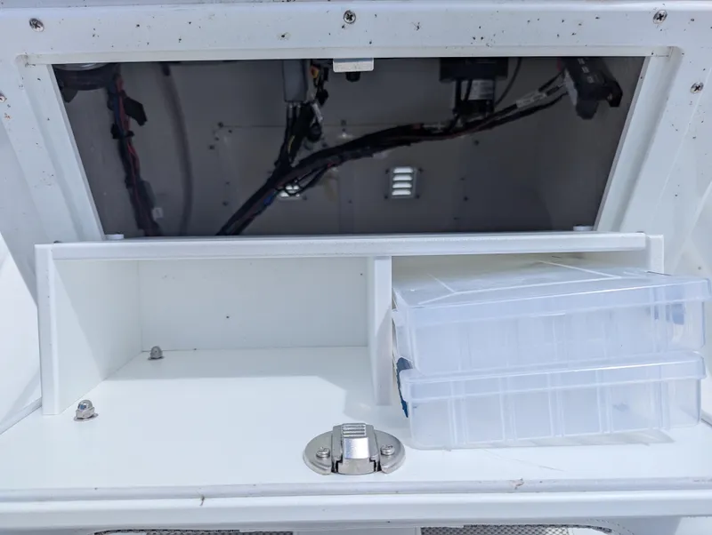 Slide: The Image of Open storage compartment in a 2025 Frontier 2104, featuring organized wiring and a clear plastic box. - 7