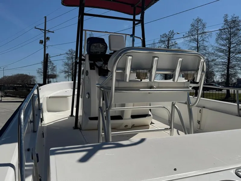 Slide: The Image of 2002 Boston Whaler 220 Dauntless boat interior with seating and console, under clear blue sky. - 11
